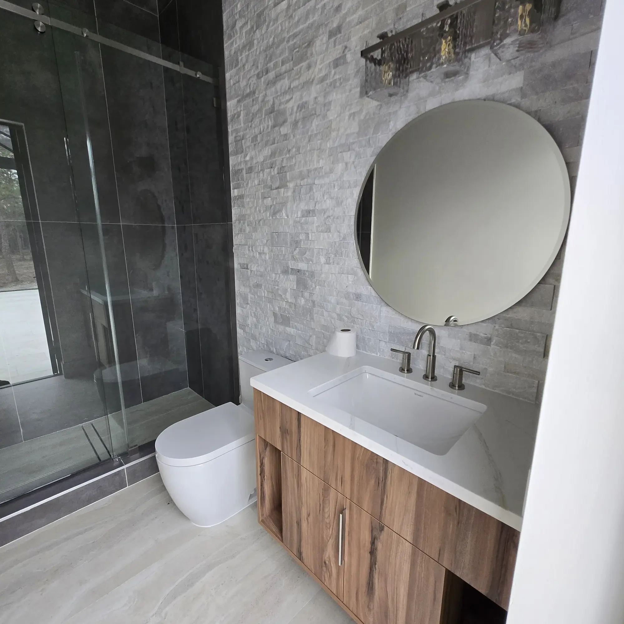 Walnut floating bathroom vanity beside a glass shower