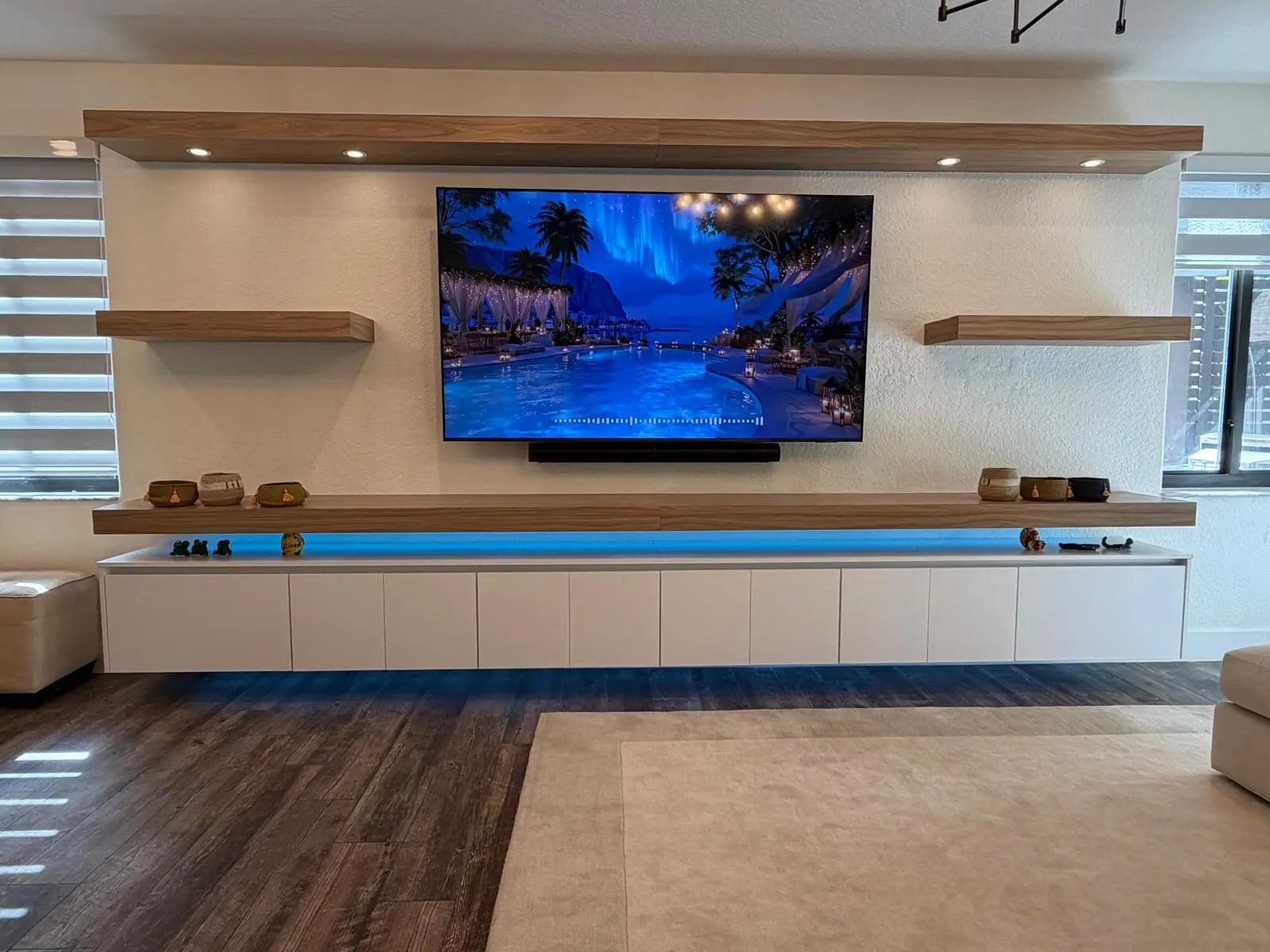 Custom floating media wall with oak shelving and integrated lighting