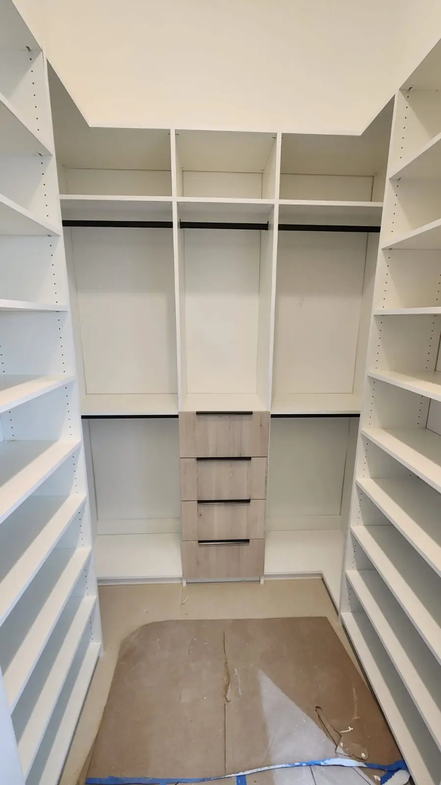 Finished white walk-in closet with shelving, hanging zones and drawers